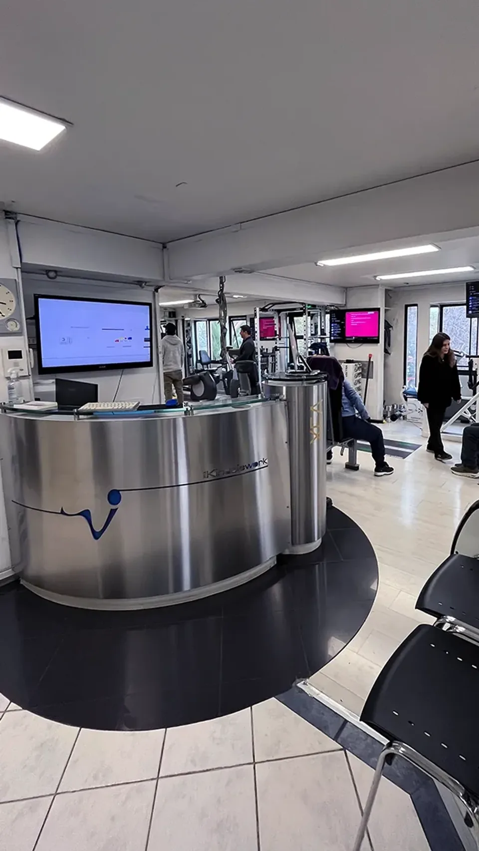 Recepción del centro de kinesiología KinesicWork con vista a la sala de rehabilitación y máquinas de ejercicio terapéutico